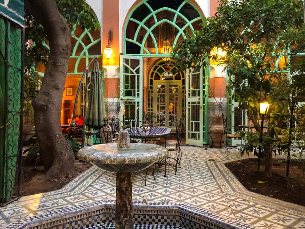 Riad binnenplaats met veel natuur en ramen. Fontein in het midden.